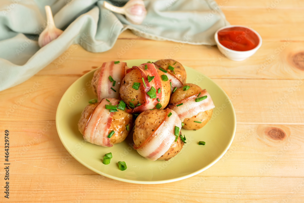 Plate of tasty baked potatoes with bacon on wooden background