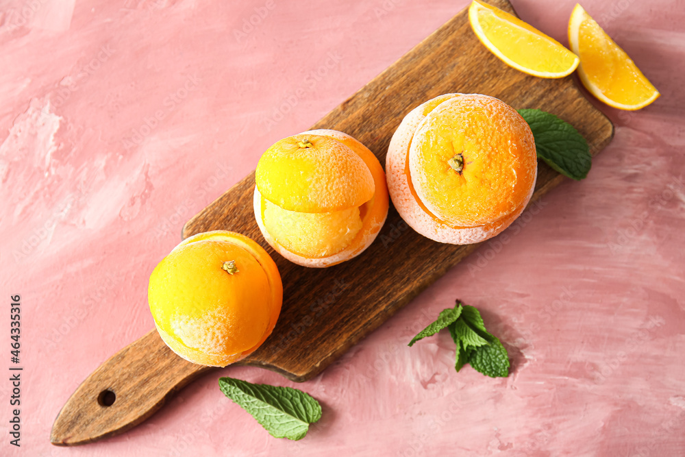 Tasty ice creams in orange peels on color background