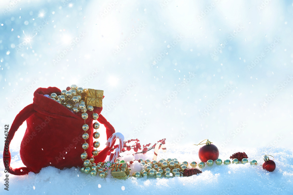 Winter Holidays background with red santa bag. Christmas balls and gift box on snow. New Year greeti