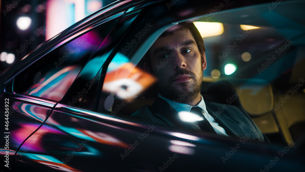 Handsome Businessman in a Suit Commuting from Office in a Backseat of His Car at Night. Entrepreneur