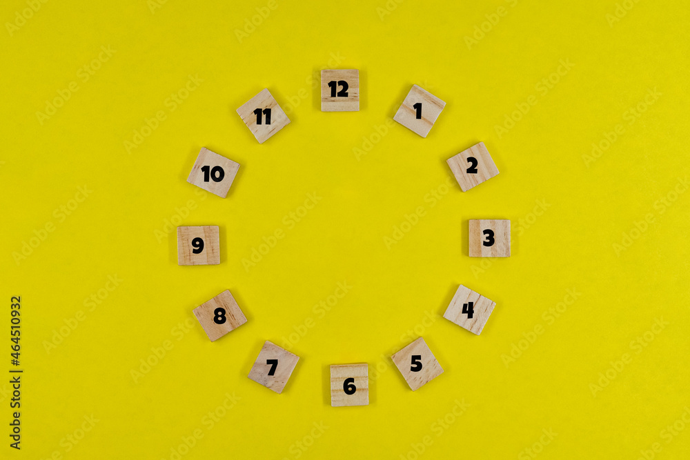 Wooden clock dial on yellow paper background