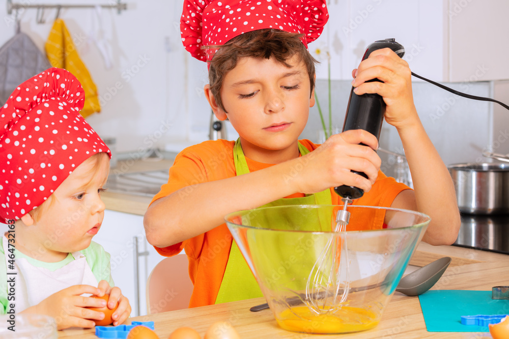 Boys mix eggs in a bowl to create dough at kitchen