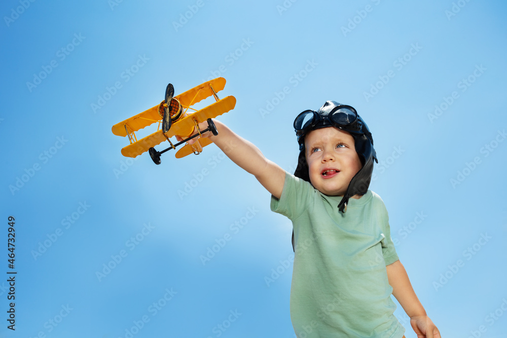 Portrait of a boy with airplane toy over blue sky