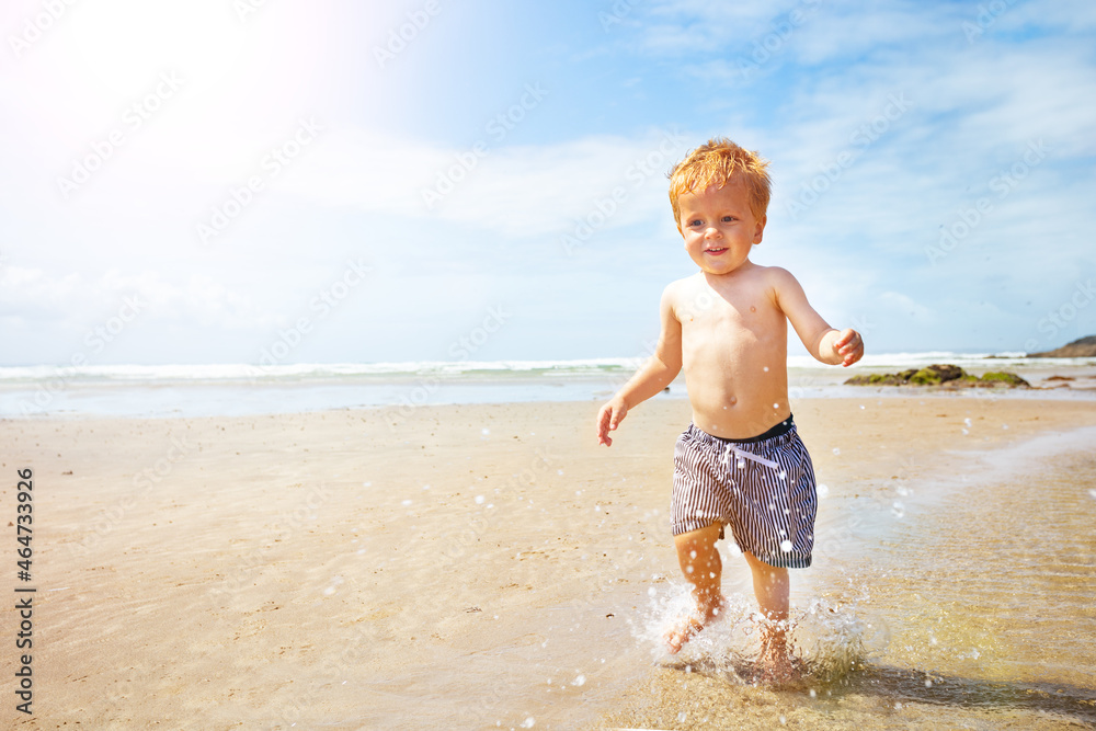 Kid boy run fast and splash on the sand sea beach