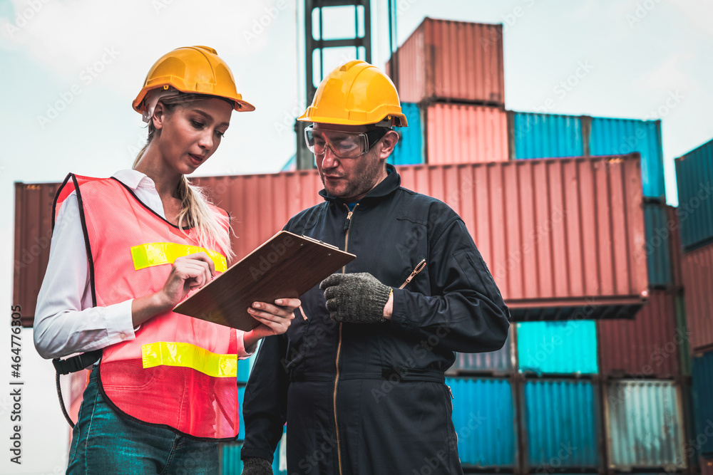 Industrial worker works with co-worker at overseas shipping container yard . Logistics supply chain 