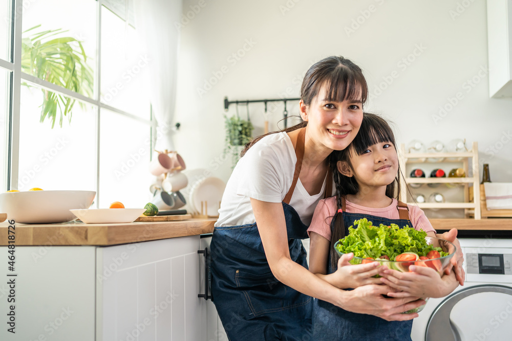 亚洲美女妈妈抱着沙拉碗和小孩的肖像。