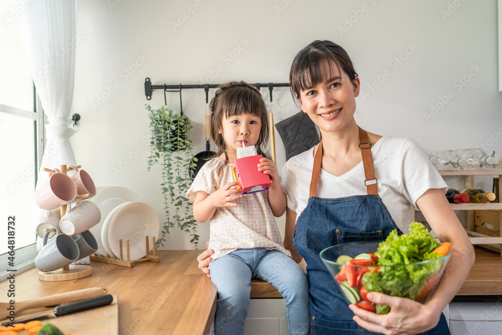 亚洲美女妈妈抱着沙拉碗和小孩的肖像。