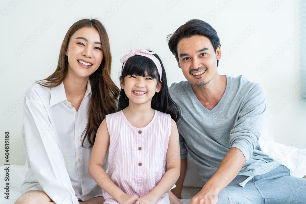 Portrait of Asian happy family smile and look at camera on bed at home. 