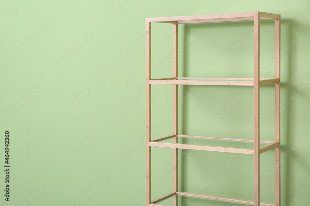 Stylish wooden shelf unit on green background, closeup