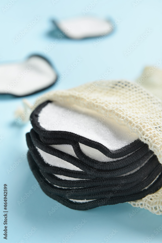 Bag with reusable cotton pads on color background, closeup