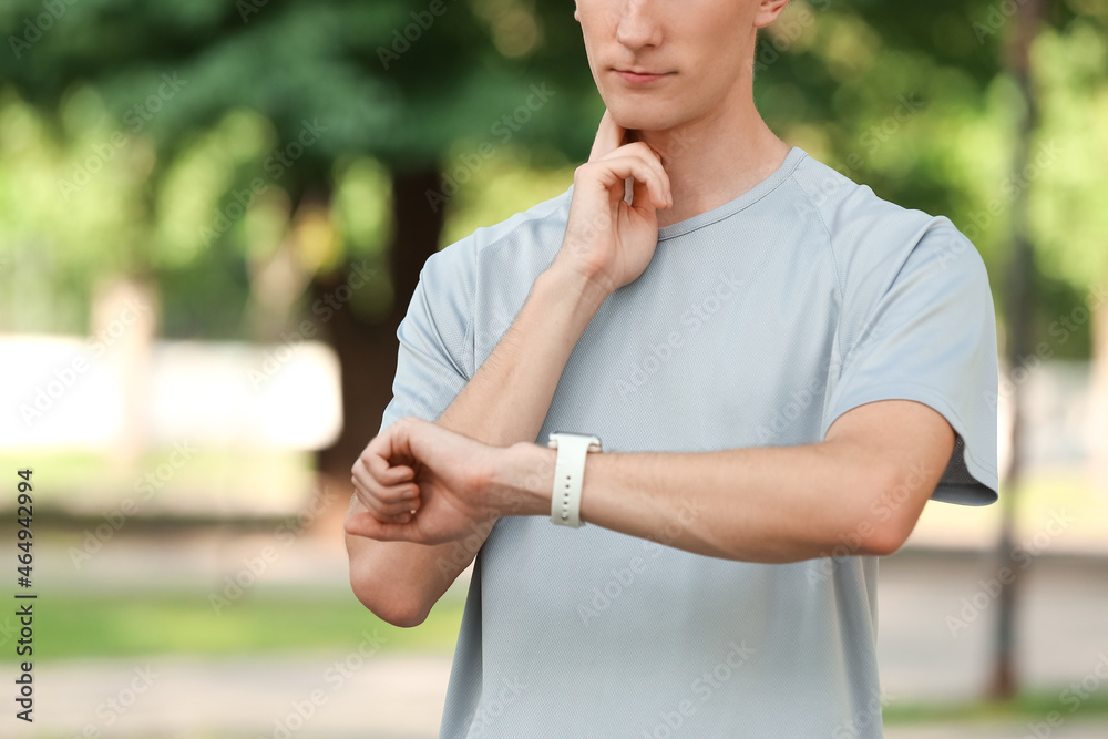 Sporty male runner checking pulse outdoors