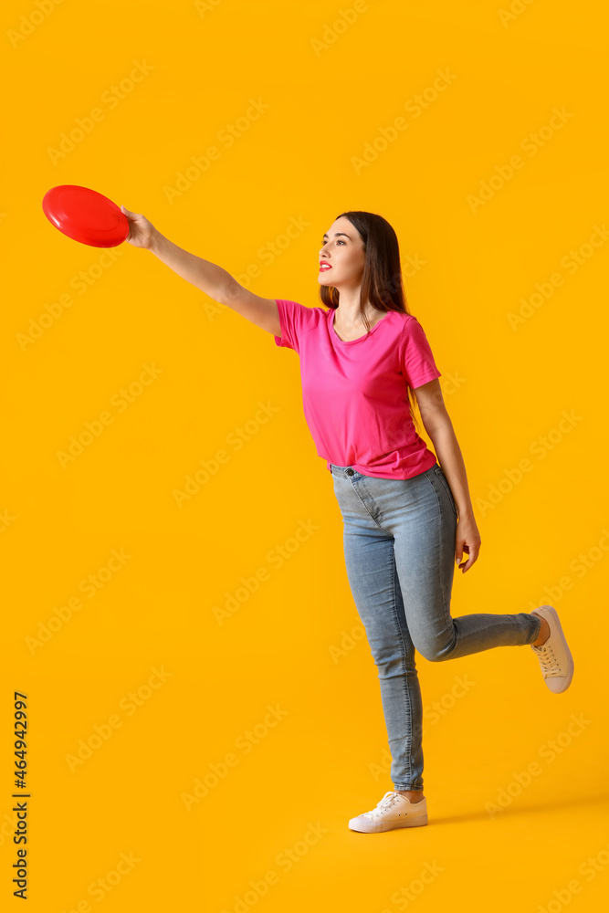 Beautiful young woman playing frisbee on color background