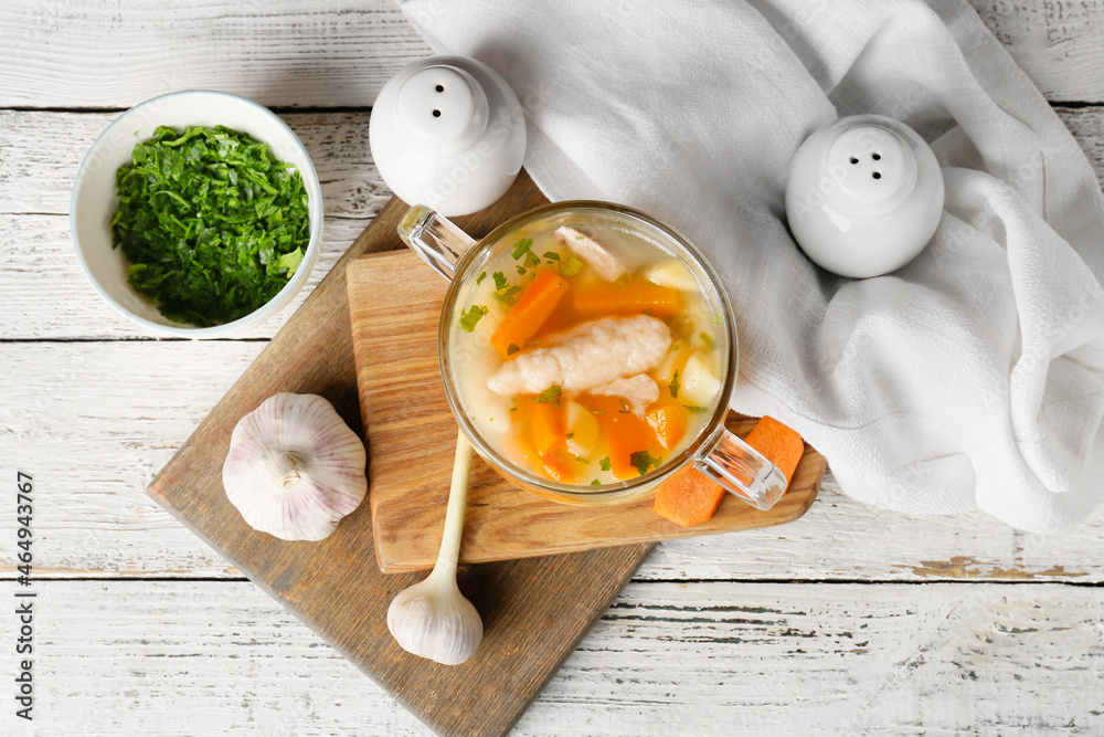 Glass bowl with tasty dumpling soup on light wooden background