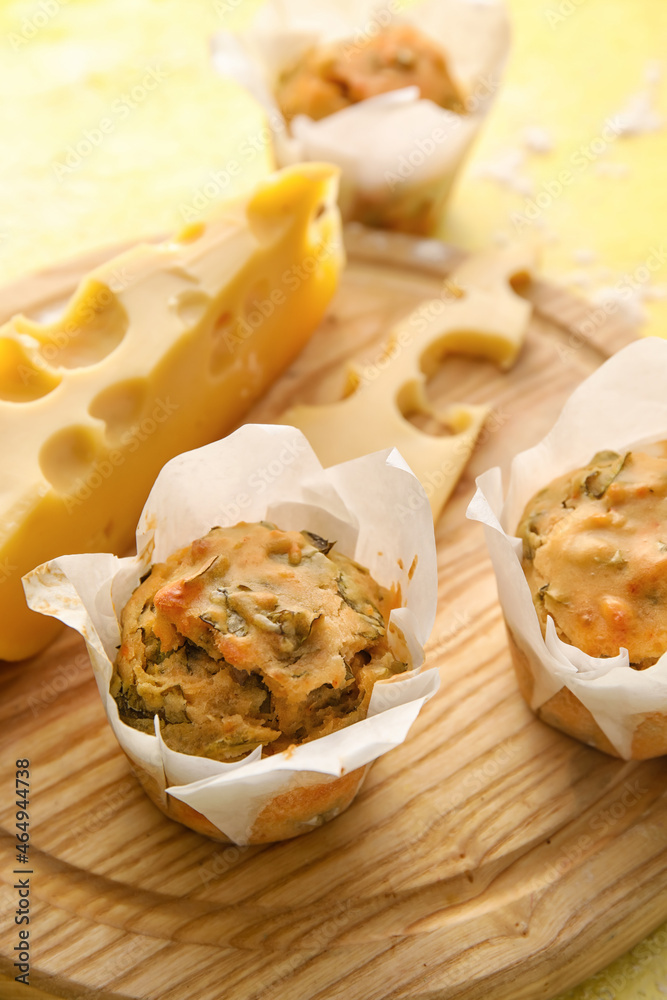 Wooden board with tasty spinach muffins and cheese on table