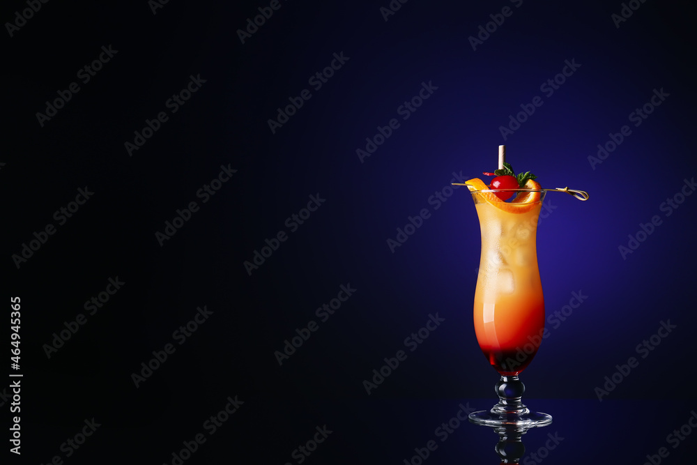 Glass of tasty Tequila Sunrise cocktail on dark color background