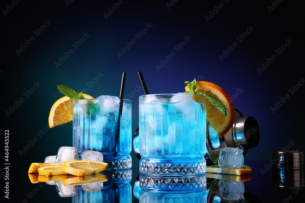 Glasses of Blue Lagoon cocktail on dark color background