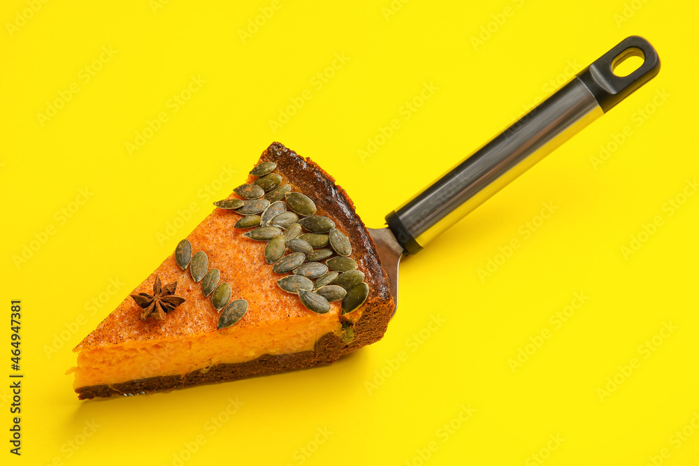 Spatula with piece of delicious pumpkin pie on yellow background