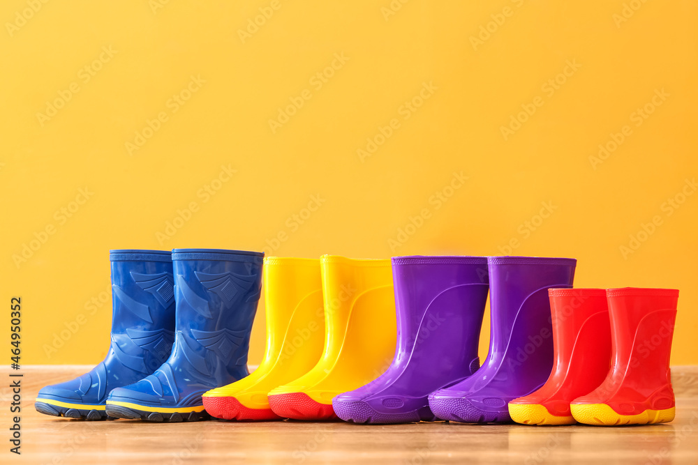 Many rubber rain boots near color wall