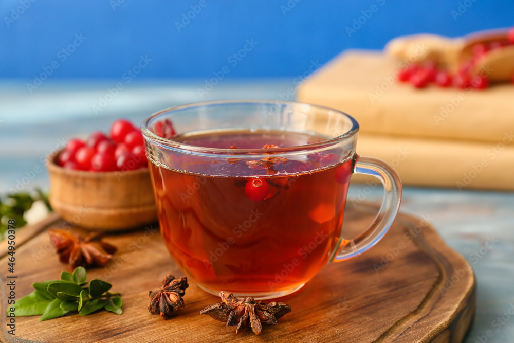 Glass cup with lingonberry tea and berries on table, closeup