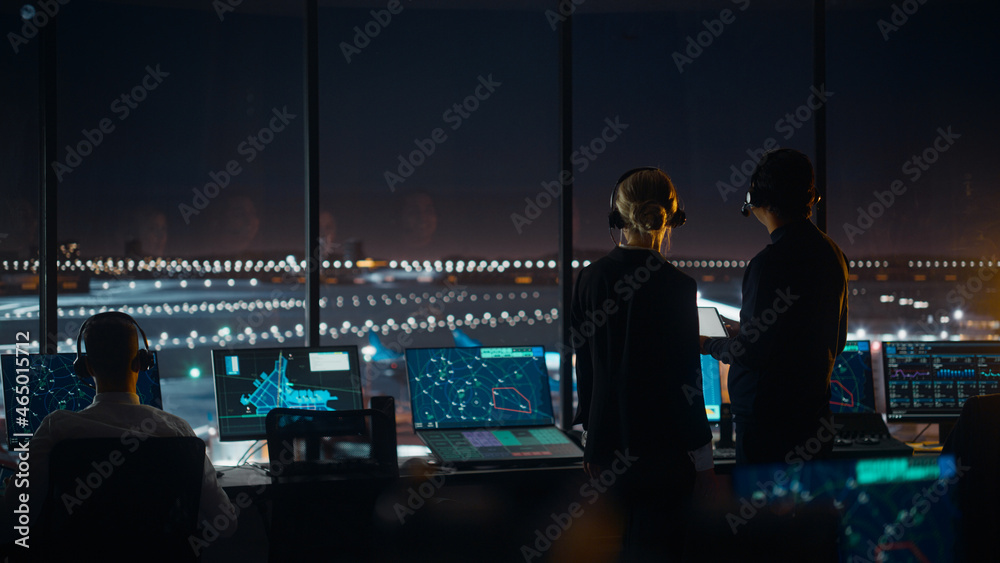 Female and Male Air Traffic Controllers with Headsets Talk in Airport Tower at Night. Office Room Fu