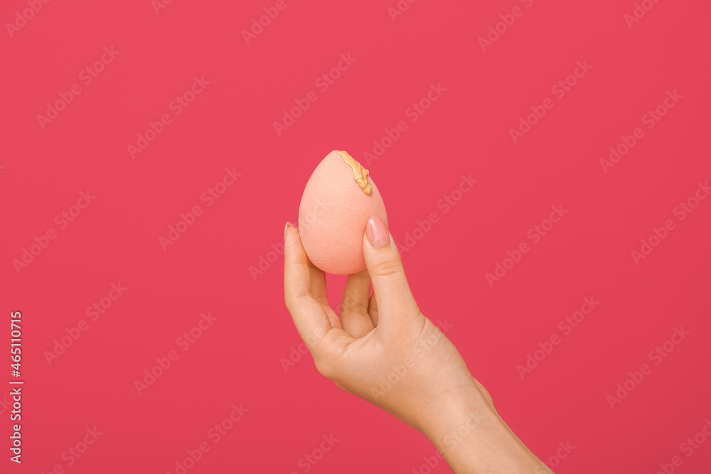 Female hand with stylish makeup sponge on color background