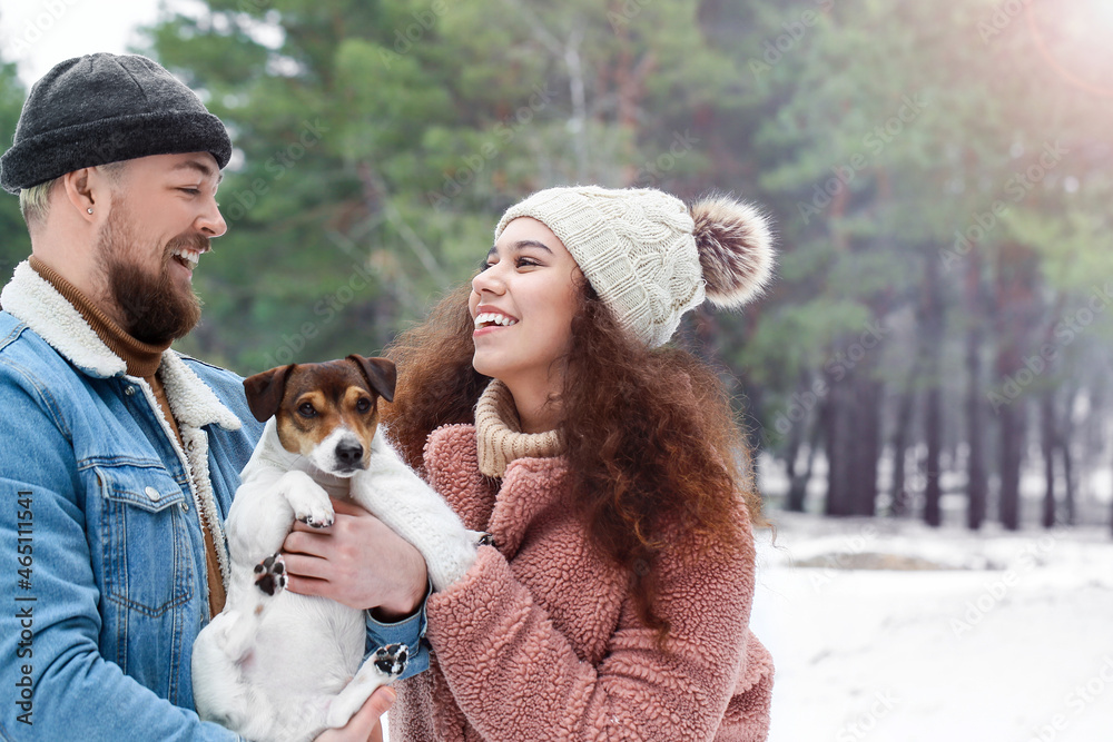 Happy young couple with dog in forest on winter day