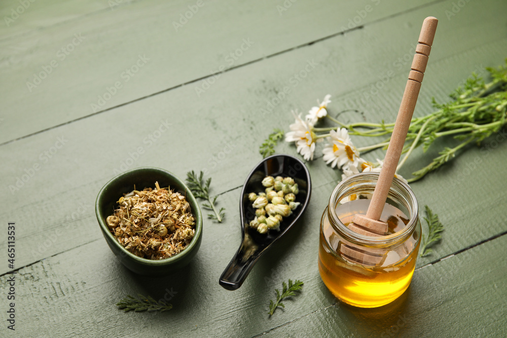 Composition with jar of sweet honey and chamomile flowers on color wooden background