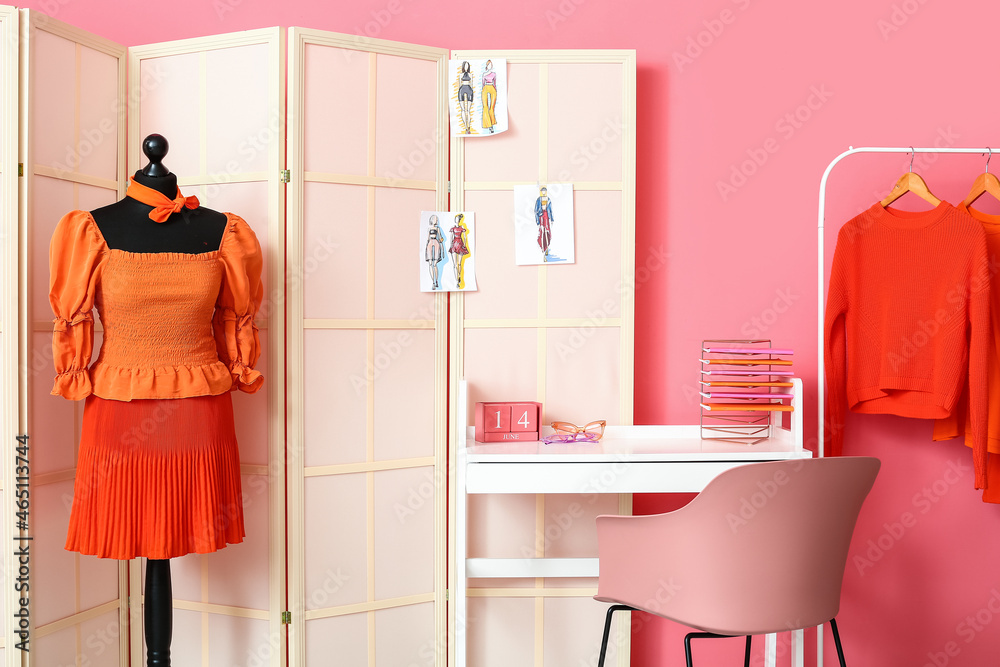 Stylists workplace with mannequin, clothes and folding screen near pink wall