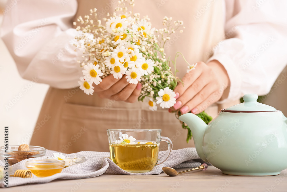 桌子上有洋甘菊花、茶壶和茶杯的女人