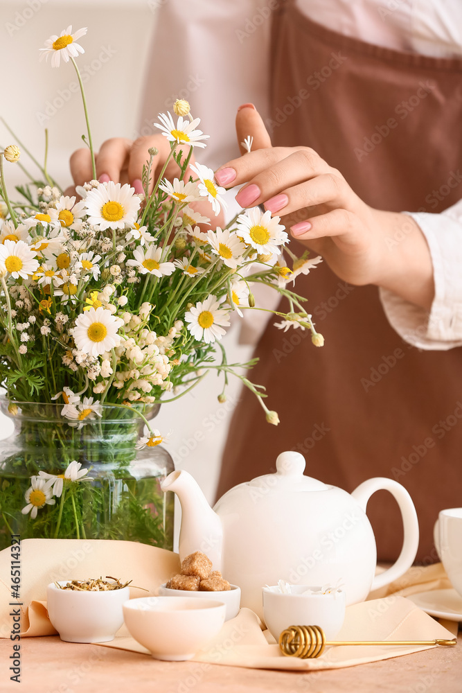 桌上摆着洋甘菊花和茶壶的女人