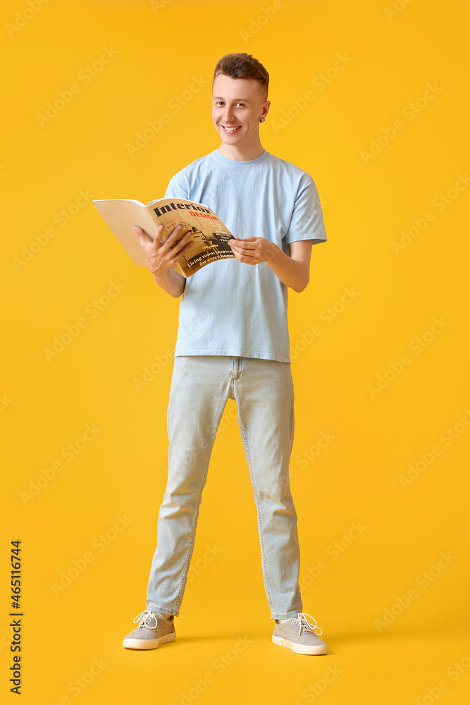 Young man reading magazine on yellow background