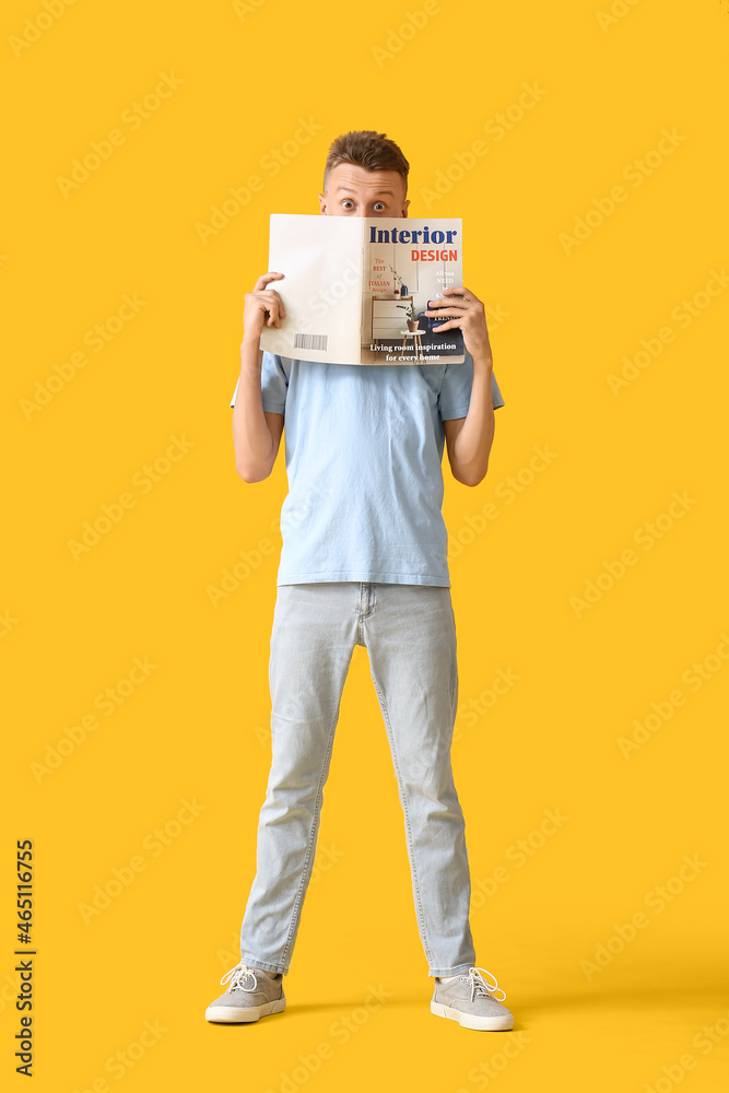 Young man reading magazine on yellow background