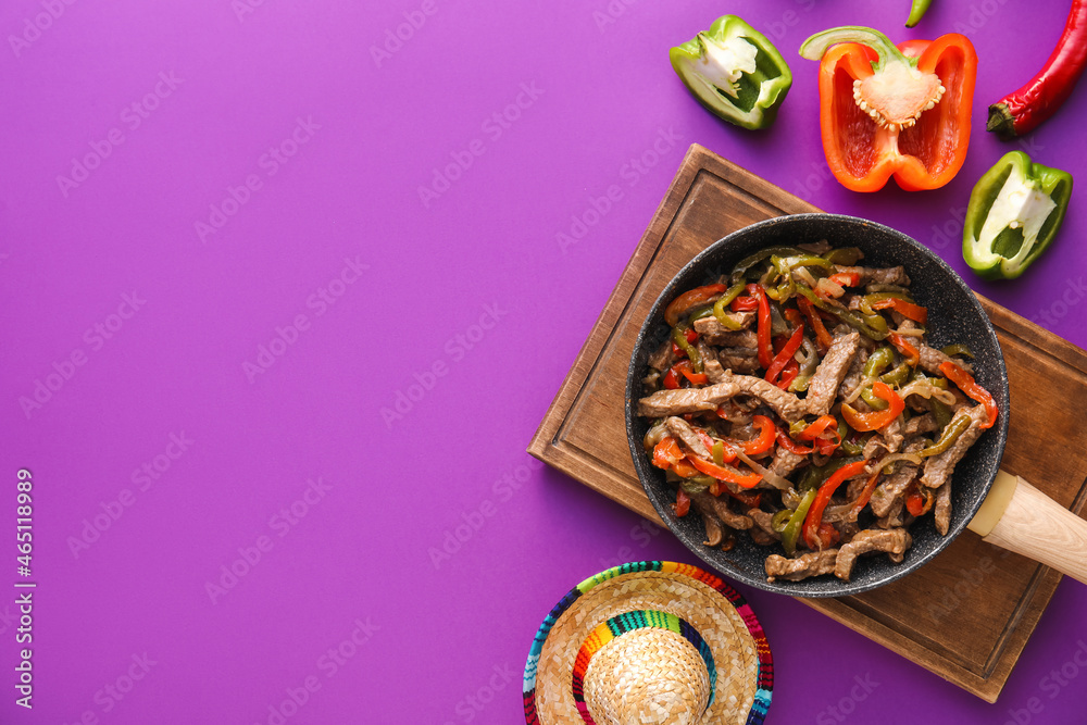 用美味的Fajita牛肉和紫色背景的墨西哥帽煎平底锅