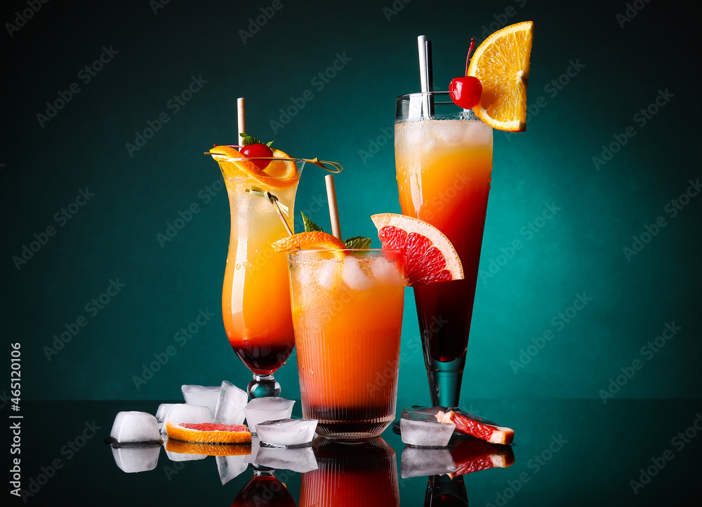 Glasses of tasty Tequila Sunrise cocktail on dark color background