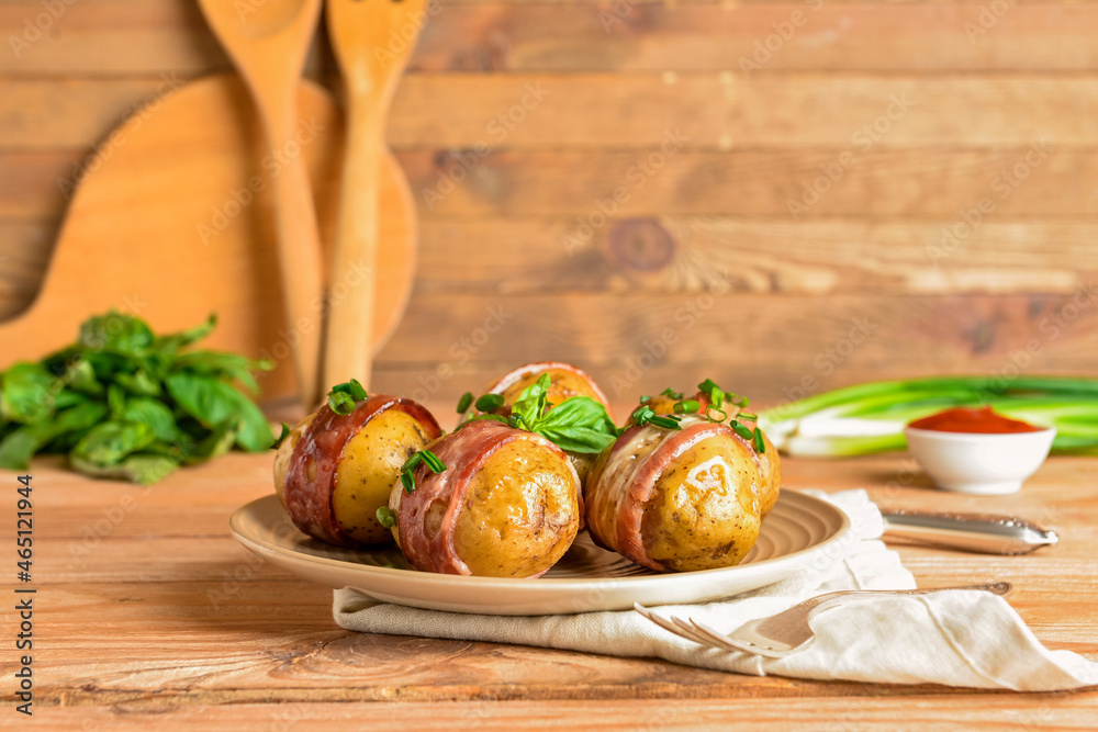 Plate of tasty baked potatoes with bacon on wooden background