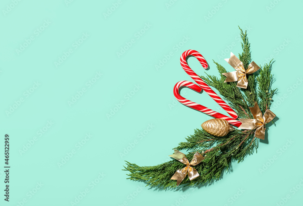 Christmas composition with candy canes, coniferous branches and decorations on color background