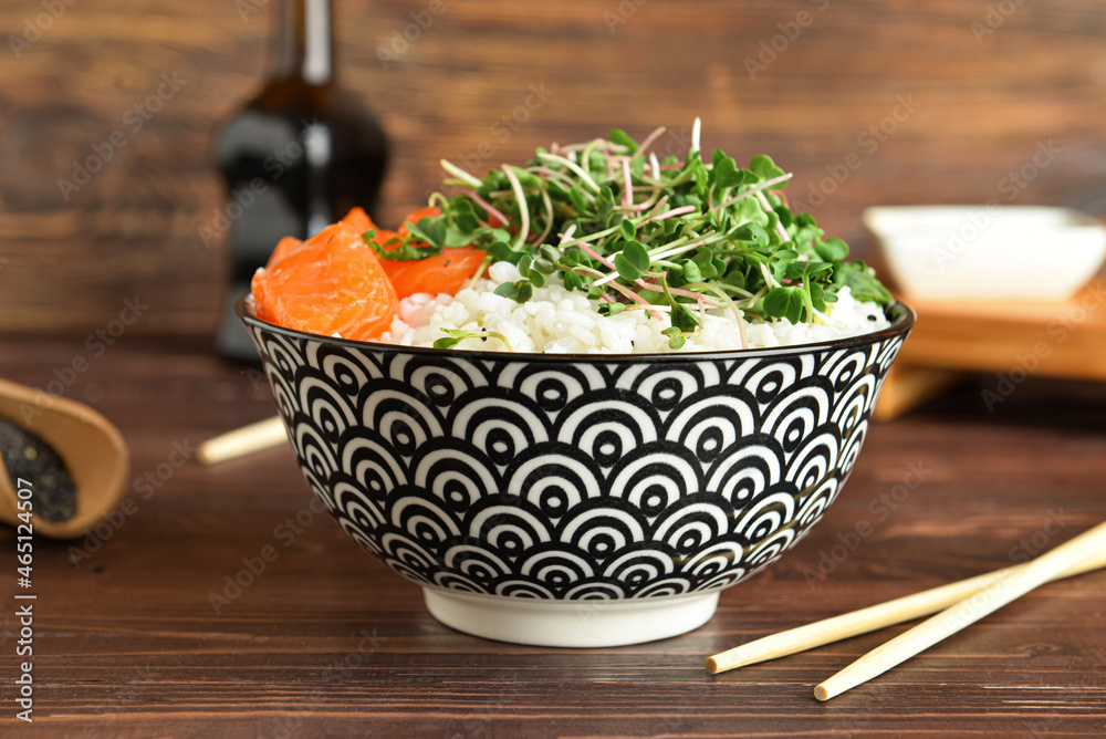 Tasty poke bowl with salmon and tofu cheese on wooden table, closeup