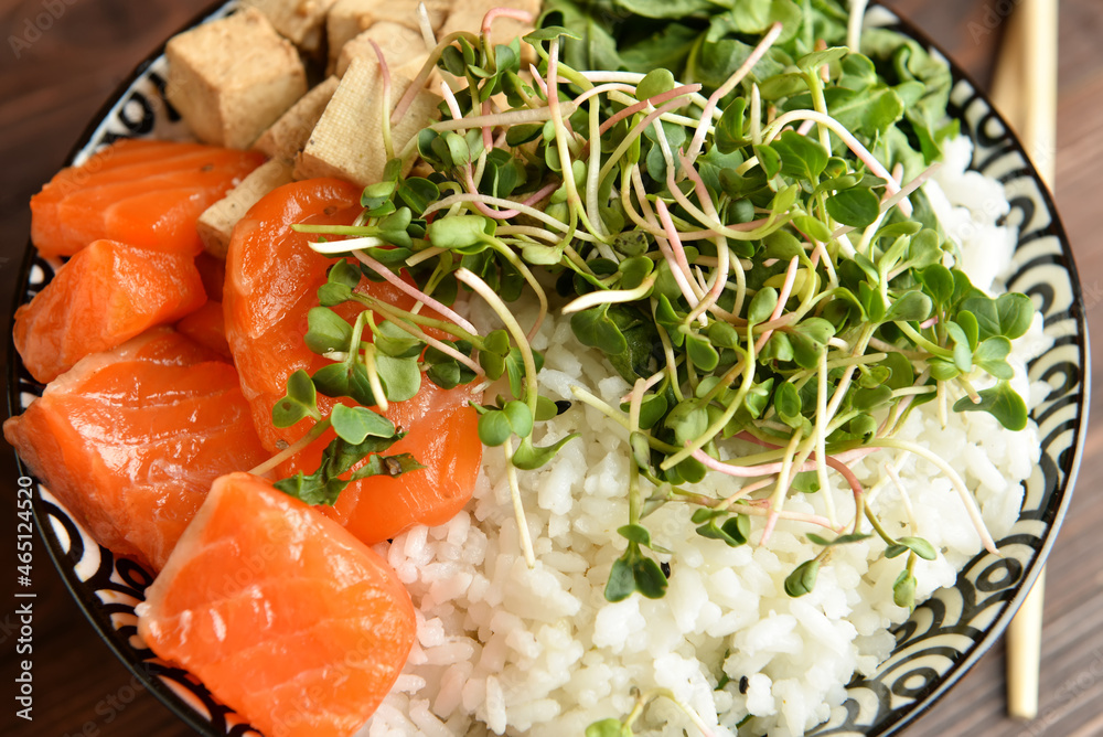 Tasty poke bowl with salmon and tofu cheese on table, closeup