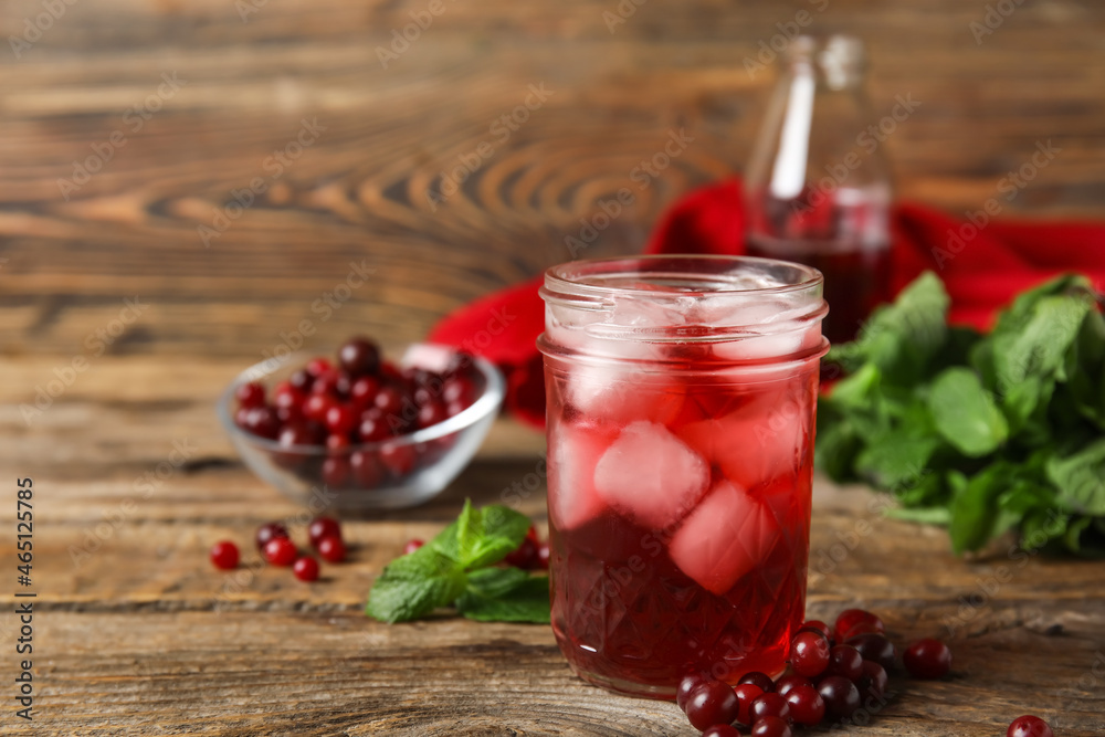 Glass with healthy cranberry juice on wooden background