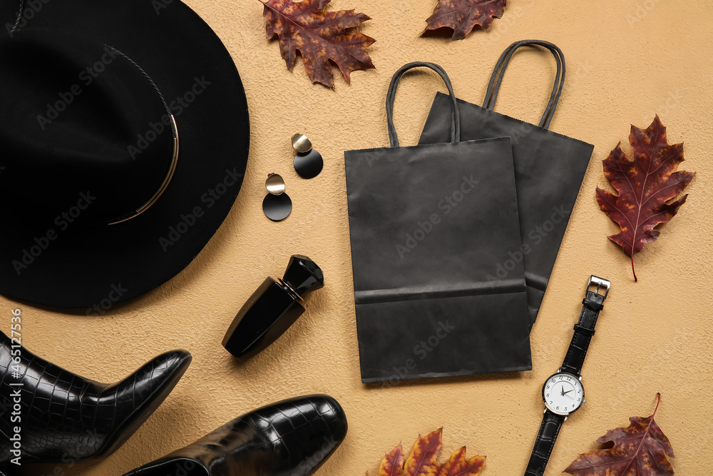 Stylish female accessories, paper bags and dry leaves on color background, closeup. Black Friday sal