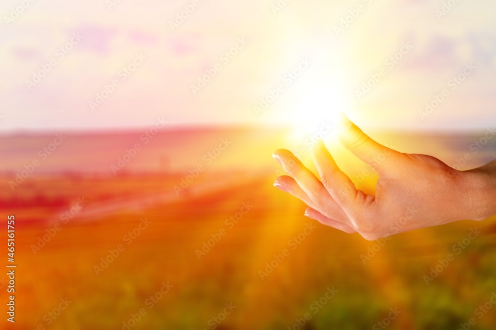 young woman raising hands praying at sunset light