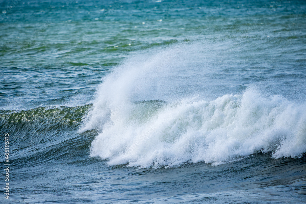 Beautiful early morning ocean waves with spray been blown by strong winds.