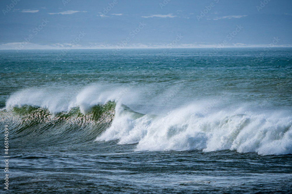 Beautiful early morning ocean waves with spray been blown by strong winds.