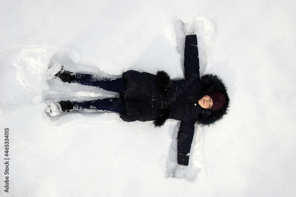 Happy girl lying on snow in winter