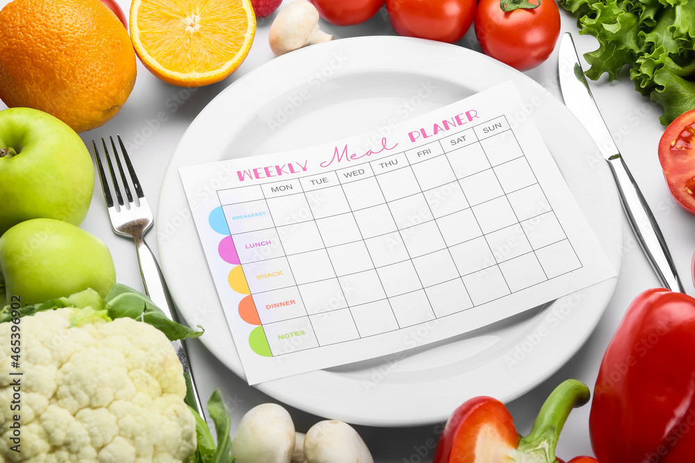 Plate with meal plan and healthy products on white background