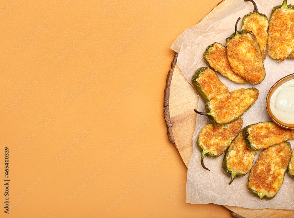 Board with tasty jalapeno poppers and sauce on color background