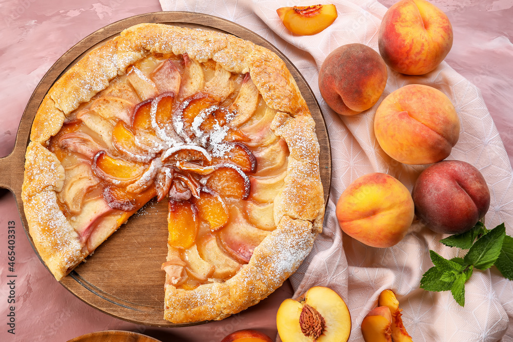 Board with tasty peach galette on color background