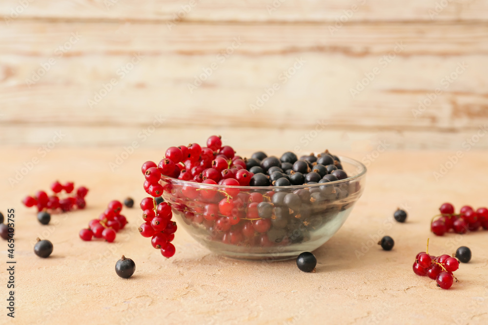 Bowl with tasty red and black currants on color background