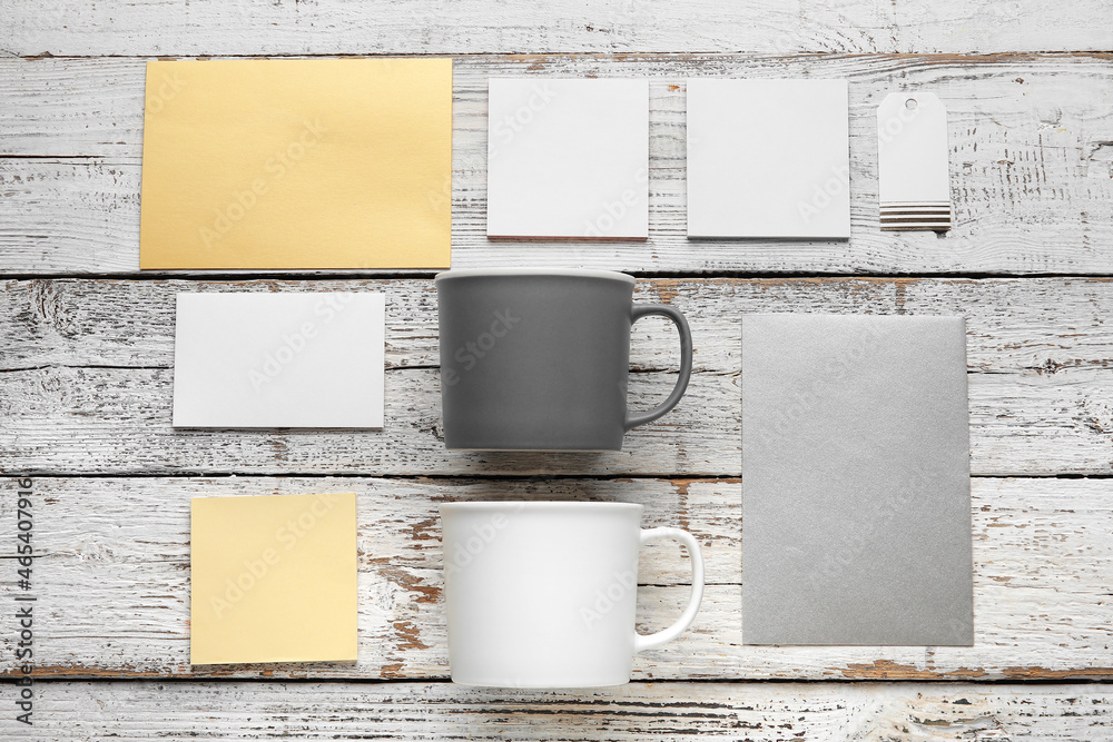 Composition with cups and blank cards on light wooden background