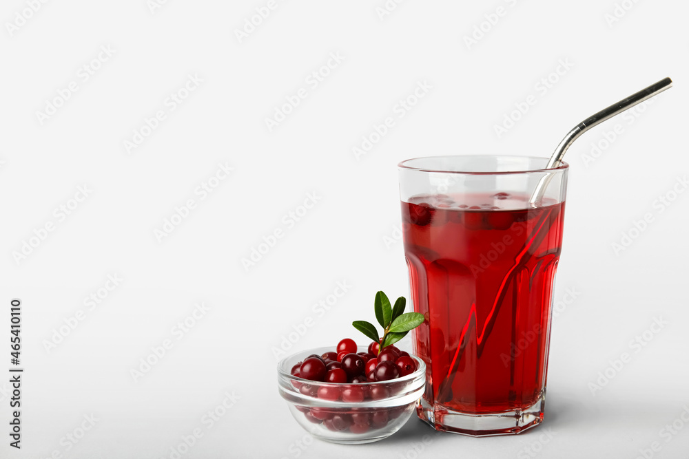 Glass with healthy cranberry juice on light background